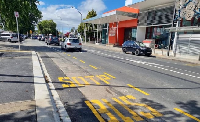 The bright yellow letters painted on Te Atatū Road spell 